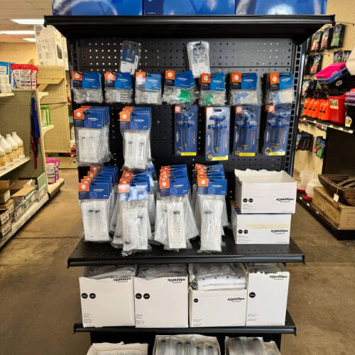 Store display with various irrigation system components, including blue and white pipe fittings and accessories, organized on shelves in a hardware store aisle.