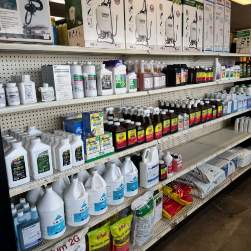 Shelves filled with various gardening supplies, featuring weed killers, fertilizers, and plant nutrients. The arrangement conveys a practical and organized setting.