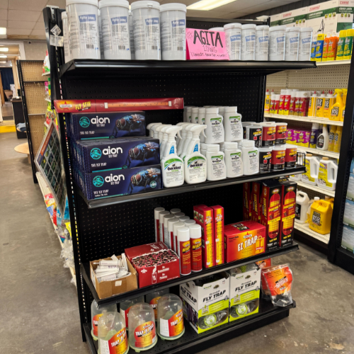 Store display featuring various pest control products, including sprays, powders, and traps on metal shelves. A pink sale sign labeled 