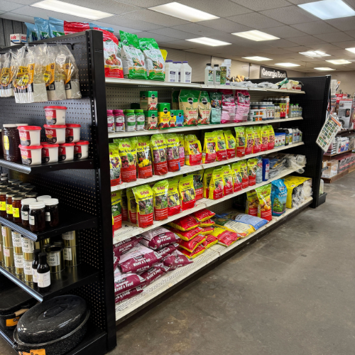 A store aisle displays colorful bags of pet food stacked neatly on shelves. Nearby are jars and bottles, all under bright fluorescent lighting. A sense of order and variety is conveyed.