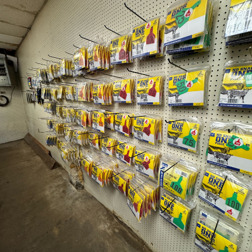 A store wall displays various fishing line packages arranged on hooks. The products have yellow labels with numbers and graphics, creating a tidy and organized look.