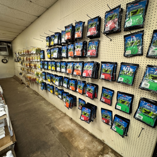 A store aisle with a pegboard wall displaying various colorful packaged products like fishing lures in neat rows. The setting is organized and practical.