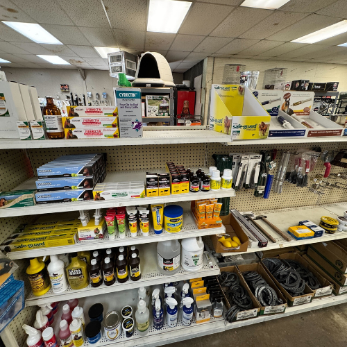 A store shelf filled with various pest control products, including sprays, traps, and protective gear. Bright lighting highlights the organized display.