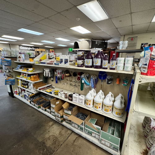 A well-lit store aisle with shelves displaying various agricultural products, including animal feed, grooming tools, and cleaning solutions in a neat arrangement.